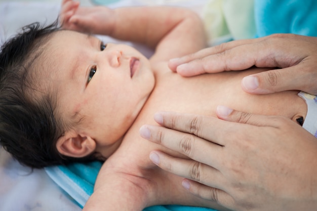 Massage de bébé nouveau-né asiatique mignonne. Mère masser son joli ventre de bébé.