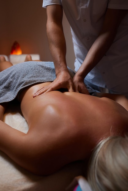 Photo massage corporel une femme se faisant masser dans le salon de spa un masseur travaillant sur son dos