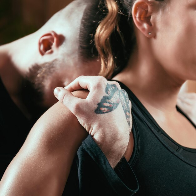 Photo massage du cou et des épaules en shiatsu, assis sur le sol et portant des vêtements noirs.