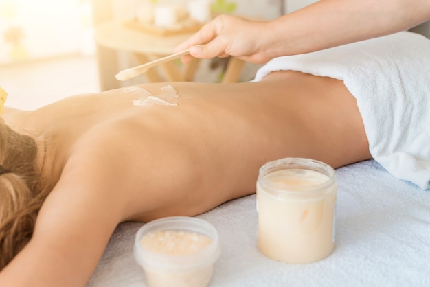 massage du dos pour une jeune femme dans un salon spa, frotter la peau du corps