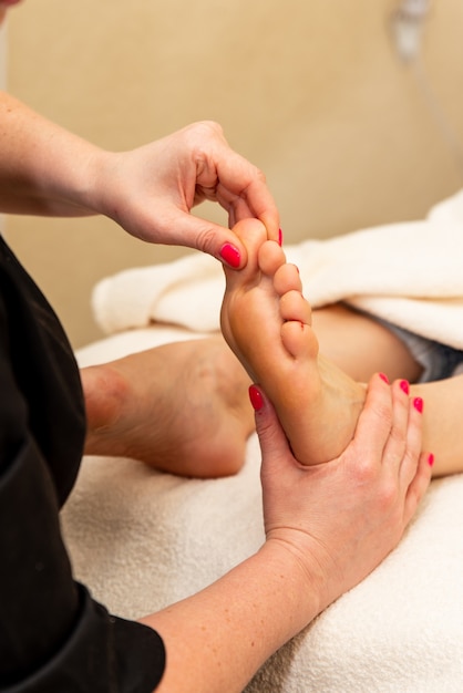 Massage du pied humain dans le salon spa. Prévention des douleurs aux jambes. Le maître de pédicure donne un massage des pieds.