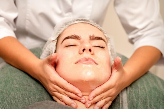 Massage du visage Belle jeune femme blanche caucasienne ayant un massage facial avec les yeux fermés dans un salon de spa