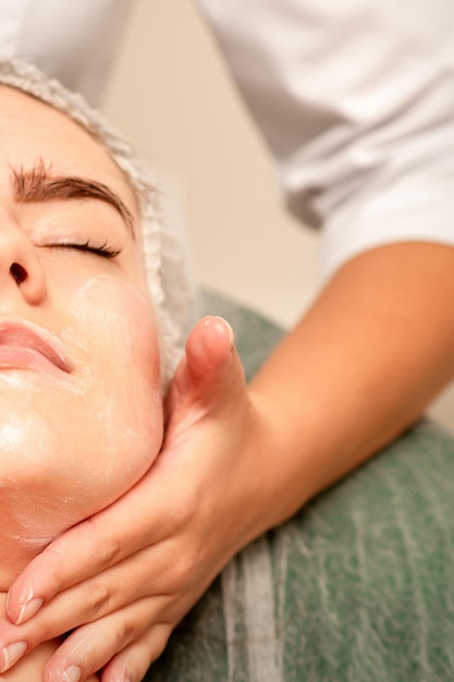 Massage du visage Belle jeune femme blanche caucasienne ayant un massage facial avec les yeux fermés dans un salon de spa