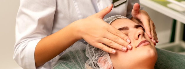 Massage du visage Belle jeune femme blanche caucasienne ayant un massage facial avec les yeux fermés dans un salon de spa