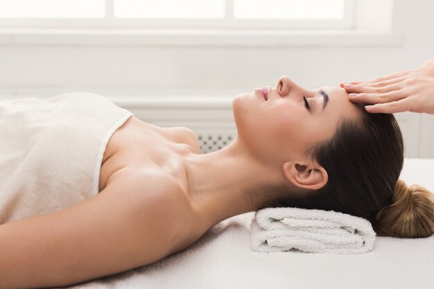 Massage du visage. Concept de spa, de villégiature, de beauté et de santé. Belle femme recevant un traitement du visage professionnel, espace de copie, vue latérale