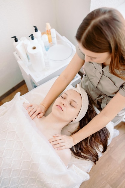 Photo massage du visage gros plan d'une jeune femme recevant un massage spa dans un salon de beauté spa soins de la peau et du corps cosmétologie faciale photo verticale