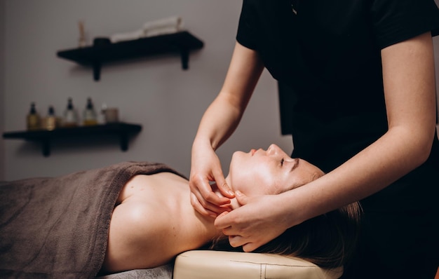 Massage du visage Gros plan d'une jeune femme recevant un traitement de massage spa au salon de beauté Spa soins de la peau et du corps Traitement de beauté du visageCosmétologie