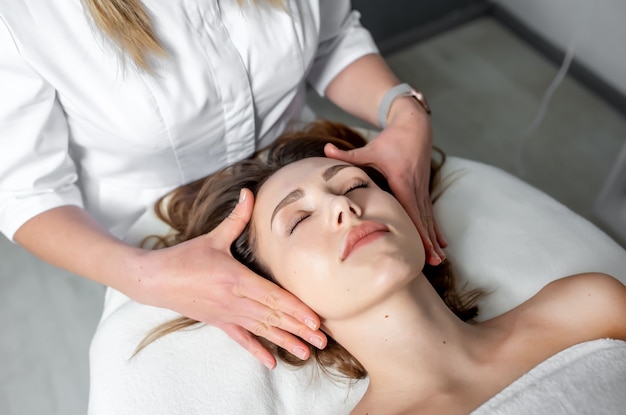 Massage du visage de la jeune femme recevant un massage spa dans un spa de beauté. Cosmétologie.