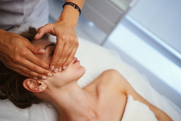 Photo massage du visage jeune jolie femme ayant un massage du visage dans le salon photo de haute qualité