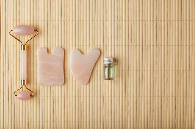 Massage Gua Sha à Base De Quartz Rose Naturel, Pierre De Jade Et Huile, Sur Fond De Bambou Pour Les Soins Du Visage Et Du Corps.