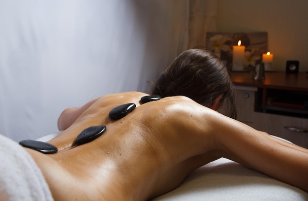 Massage de pierres sur le dos d'une cliente dans un salon de spa contre