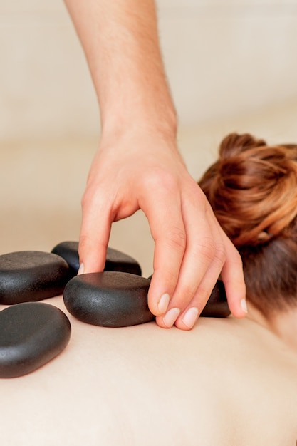 Massage des pierres sur le dos de la femme.