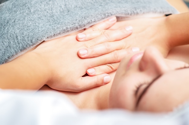 Massage de la poitrine de la femme par les mains du massothérapeute se bouchent.