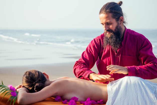 Massage relaxant ayurvédique, femme de santé dans le salon de spa se faisant masser sur la plage de vacances. Belle fille profitant de la station thermale de jour, allongée sur la procédure de traitement de la table.