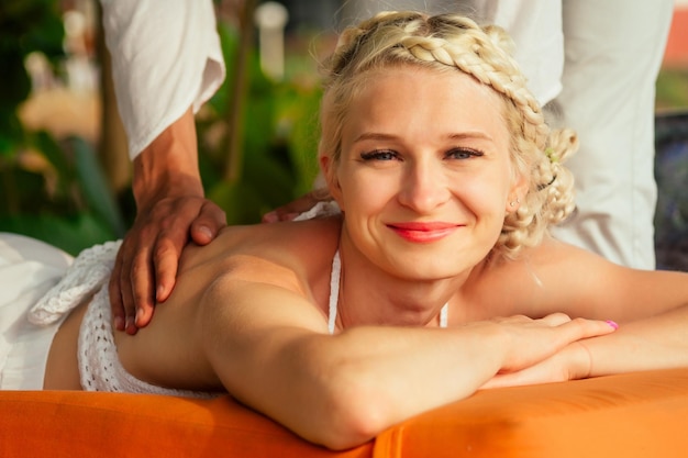 Massage relaxant ayurvédique santé beauté femme blonde heureuse dans un salon de spa se faisant masser sur la plage de vacances