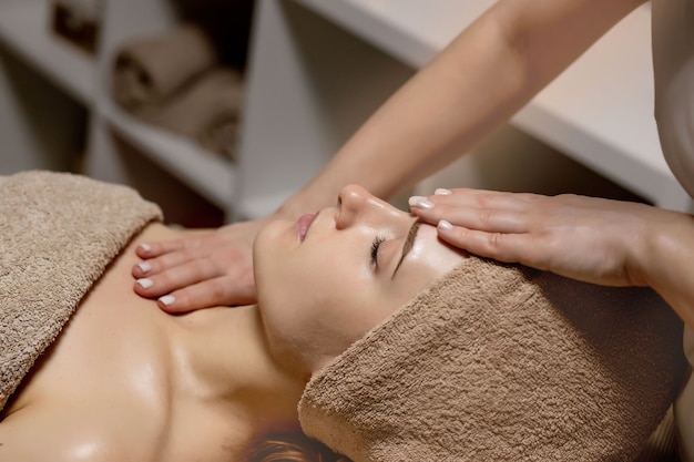 Massage relaxant. Femme recevant un massage de la tête au salon spa, vue latérale.