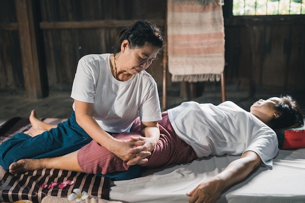 Massage et spa traitement relaxant du syndrome de bureau style de massage thaï traditionnel Asain masseuse féminine senior faisant un massage traiter la douleur au dos de la main la douleur au bras le pied et le stress pour la vieille femme fatiguée