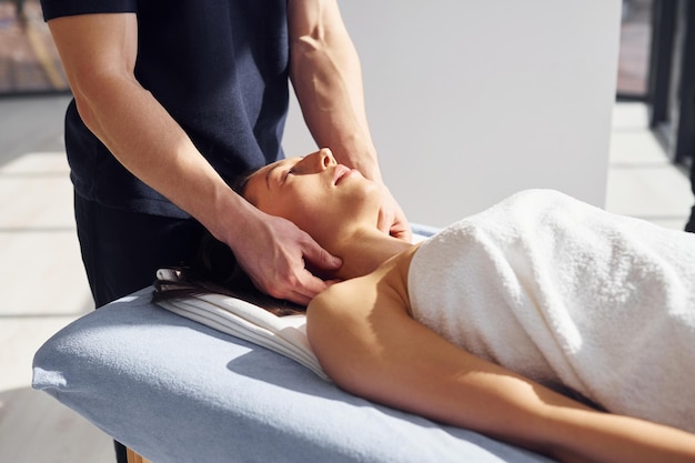 Massage de la tête Une jeune femme est allongée quand un homme lui fait une procédure au spa