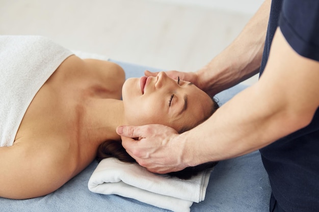 Massage de la tête Une jeune femme est allongée quand un homme lui fait une procédure au spa