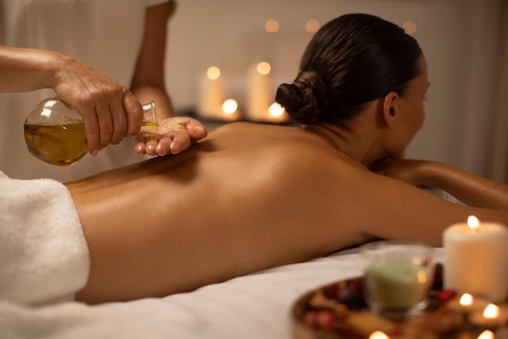 Photo massage thérapeute versant de l'huile sur la dame de retour au spa de luxe décoré avec des bougies concept de soin du corps
