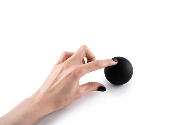 Masser la boule noire dans la main féminine pour les points de déclenchement isolés sur fond blanc Concept de libération myofasciale