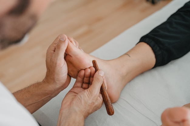 Masser le pied avec un bâton en bois