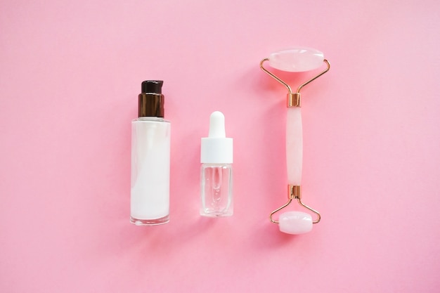 Masser avec un rouleau de quartz pour le visage avec du jade naturel rose. Outil de massage à la gouache, à l'huile de sérum de beauté. Anti-âge et lifting à domicile. Concept de massage et de relaxation de soins du visage.