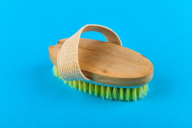 Masseur à brosse en bois. massage brosse en bois corps mou avec poil naturel, porté à la main, sur fond bleu, utilisé dans le