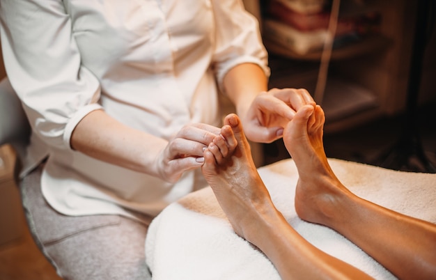 Un masseur caucasien fait un massage des pieds pour le client lors d'une procédure de spa