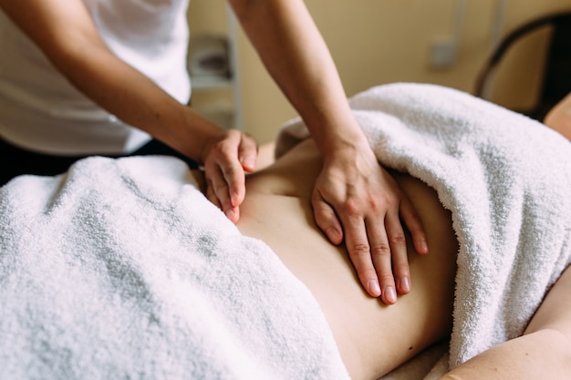 Le masseur donne un massage au ventre féminin au spa