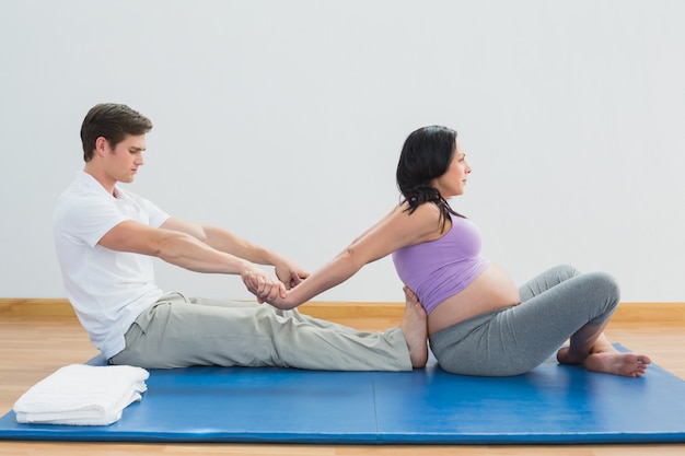 Masseur étirement des bras et des épaules des femmes enceintes sur un tapis