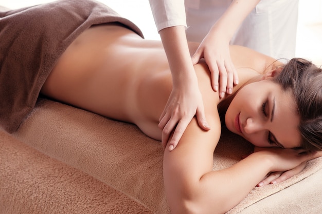 Masseur fait massage sur le corps de la femme dans le salon spa. Concept de traitement de beauté.