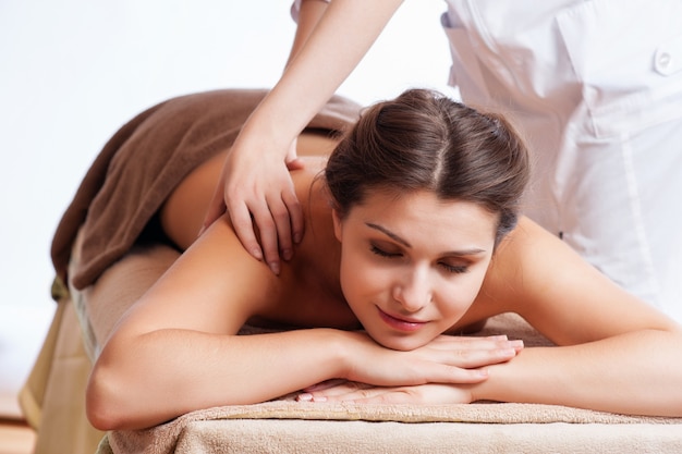 Photo masseur fait massage sur le corps de la femme dans le salon spa. concept de traitement de beauté.