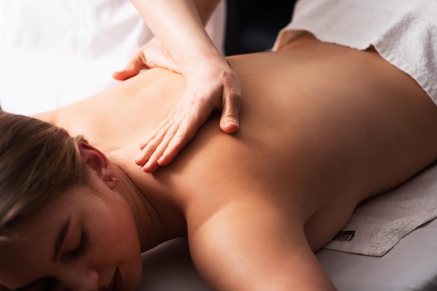 Masseur massant le dos et les omoplates d'une jeune femme sur une table de massage Concept de soins spa de massage Gros plan