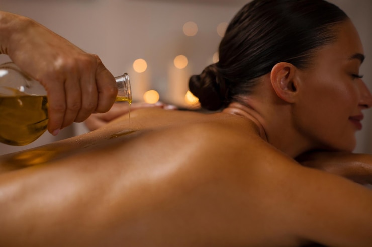 Photo un masseur professionnel versant de l'huile sur le dos d'une femme pendant une séance d'aromathérapie au spa.