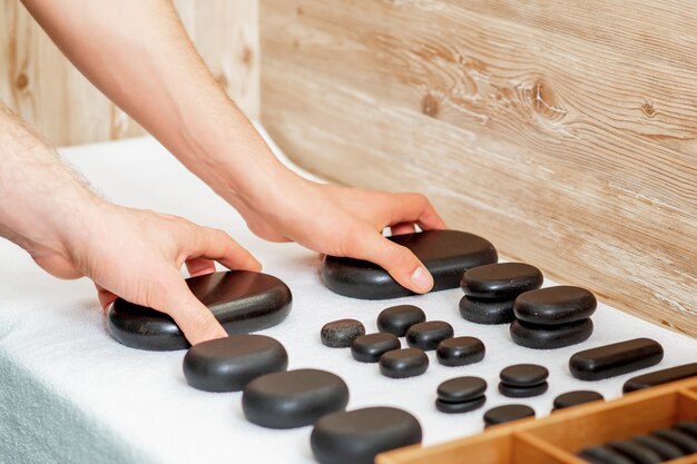 Les masseurs prennent des pierres de massage chaudes et noires.