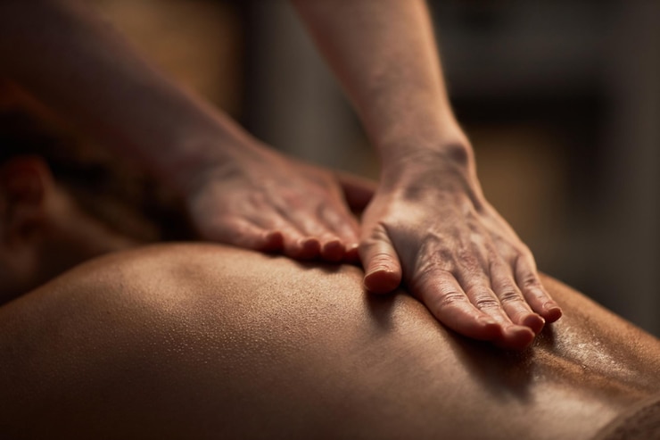 Photo masseuse appliquant de l'huile sur le dos