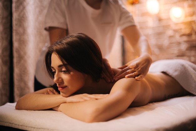 Une masseuse féminine fait un massage du dos et des épaules à une jeune femme dans un centre de spa