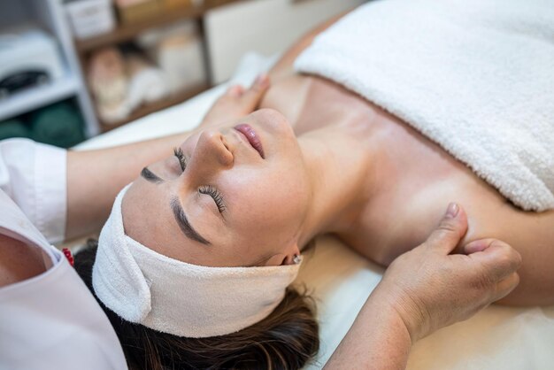 masseuse avec des mains qui travaillent masse le visage d'une cliente dans un salon de spa lifting du mode de vie sain