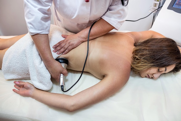 Masseuse professionnelle effectue un traitement cellulite sur tout le corps avec un appareil spécial massage anticellulite