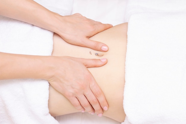 Massothérapeute massant le ventre d'une femme. Massage et soins corporels. Spa corps massage femme mains traitement.