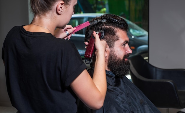 Master Barber réalise la coiffure et le coiffage avec rasoir électrique pour homme Concept Barbershop