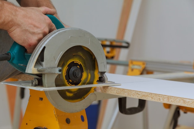 Master coupe scie électrique à main couper un morceau d'étagères en bois stratifié dans l'appartement