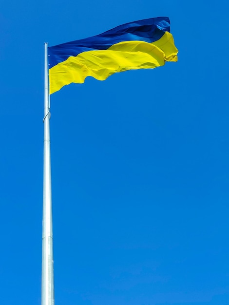 Mât de drapeau avec le drapeau de l'Ukraine contre le ciel bleu