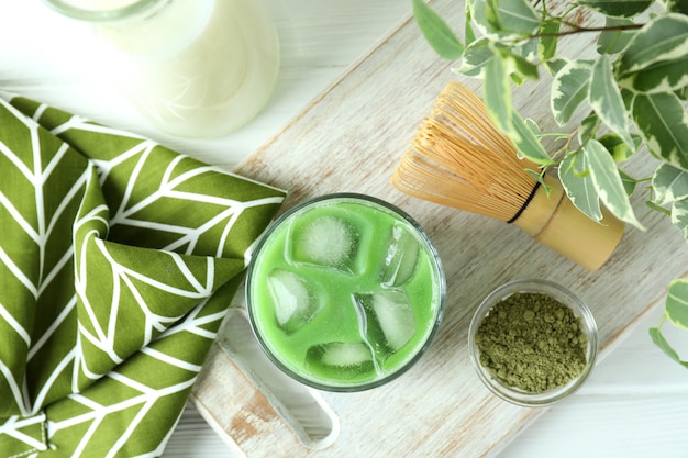 Matcha latte et accessoires pour faire sur table en bois blanc