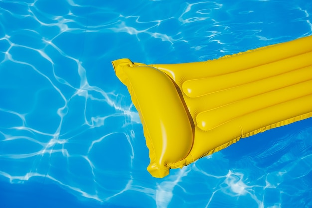 Un matelas pneumatique jaune flotte dans une piscine vide d'eau bleue Concept de vacances d'été