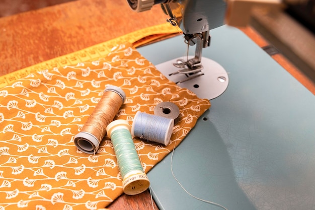 Matériel de couturier avec bobines de fil de premier plan ruban à mesurer machine à coudre et tissu orange