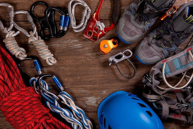 Matériel d'escalade pour l'alpinisme et la randonnée casque marteau mousqueton chaussures de trekking et autres sur fond de bois vue de dessus