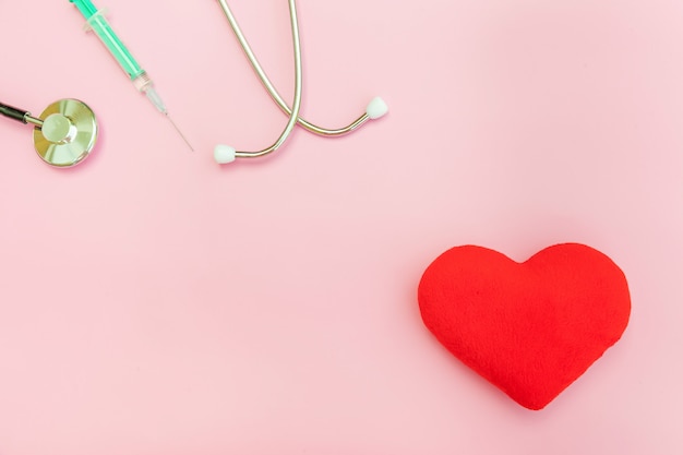 Matériel de médecine seringue stéthoscope et coeur rouge isolé sur fond rose