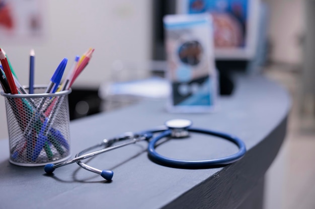 Matériel médical à la réception avec stylos et dépliants d'information à la réception de l'hôpital. Stéthoscope sur table dans la zone administrative de la clinique. Personne n'utilise de matériel médical pour contrôler les patients.